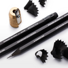 Brass pecil sharpener, three black resketch pencils on their side. Pencils are made from black wood, black eraser and a black Ferrule. Black pencil shavings The Machine Kills Fasicists printed on the side.