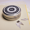 Lifestyle Picture of an Aluminum tin of Resketch Notebook Darts, sitting on top of a Resketch notebook made from 100% reclaimed, rescued and upcycled paper.